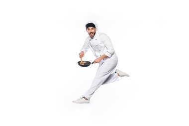 Şapkalı ve üniformalı gülümseyen şef atlıyor ve tavayı ahşap spatulayla tutuyordu. 