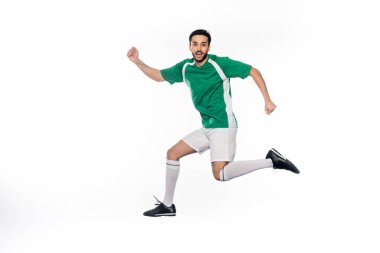 Üniformalı genç futbolcu beyazların üzerinde tek başına zıplıyor. 