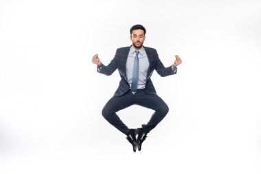 Takım elbiseli iş adamı beyaz üzerinde uçuyor ve meditasyon yapıyor. 