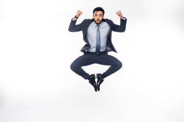 businessman in suit jumping while showing muscles on white  clipart