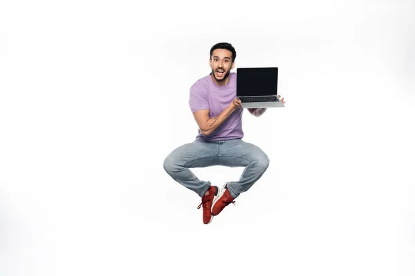 청바지와 보라색 티셔츠를 긍정적 스크린에 화면으로 노트북을 부양하는 — 스톡 사진