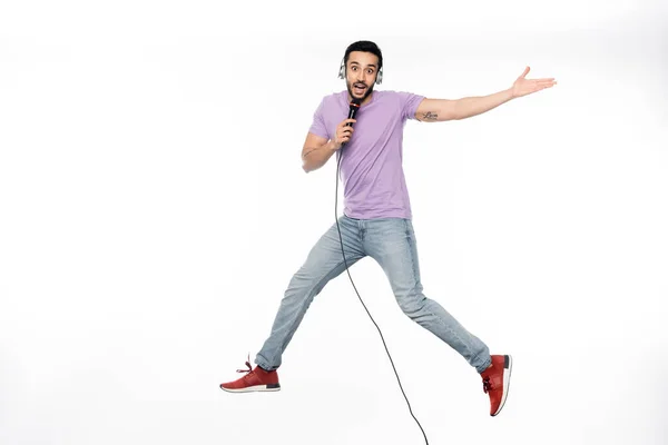 Hombre Positivo Auriculares Inalámbricos Cantando Micrófono Levitando Sobre Blanco — Foto de Stock