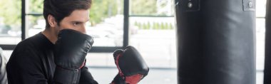 Boks eldiveni sporcusu. Spor salonunda kum torbası ve afiş. 