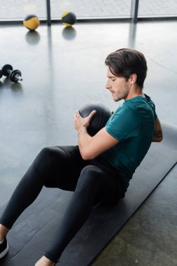 Sporcu antrenmanının yüksek açılı görüntüsü spor salonunda spor minderinde topa vuruyor. 
