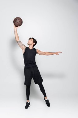 Sporcu gri arka planda yükselen basketbol topu