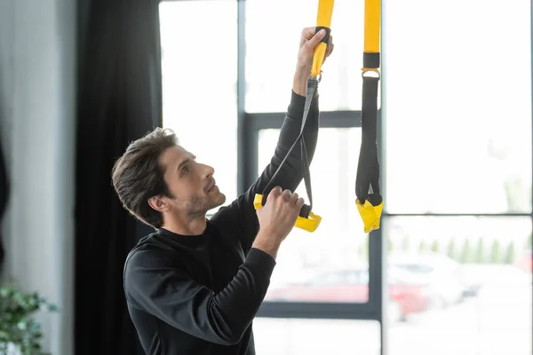 Brunette Sportsman Adjusting Suspension Straps Gym — Stockfoto