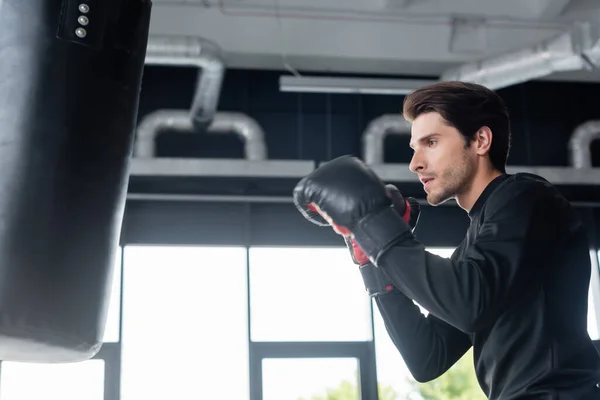 Vista Lateral Del Deportista Guantes Boxeo Mirando Borroso Saco Boxeo — Foto de Stock