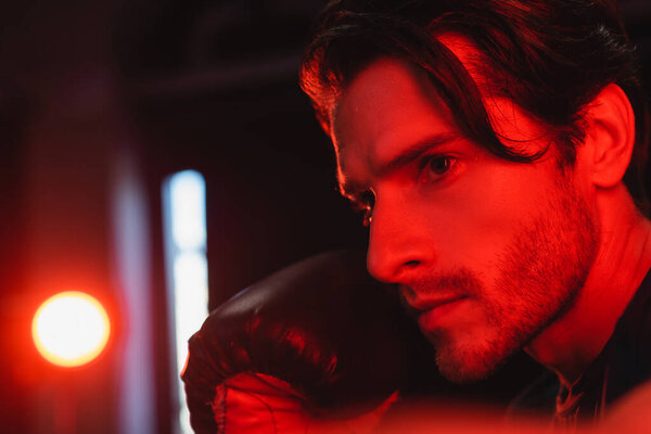 Портрет бородатого спортсмена в боксёрской перчатке на черном фоне 