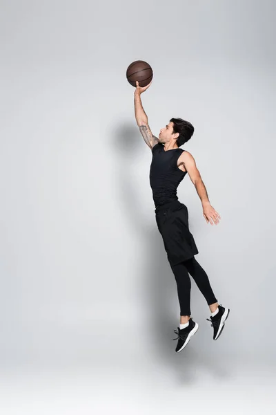 Side View Player Basketball Ball Jumping Grey Background — Stock Photo, Image