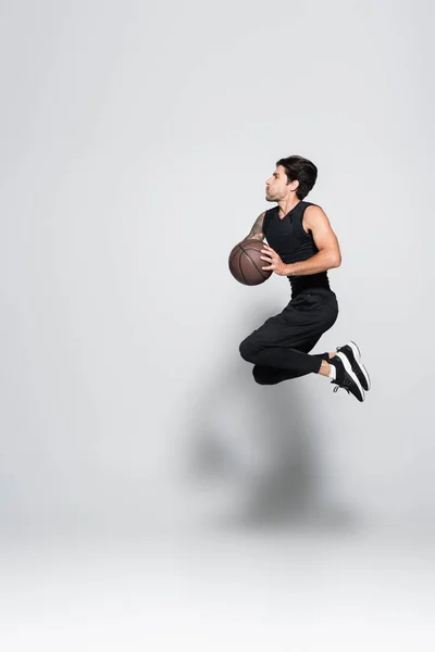 Seitenansicht Tätowierter Sportler Mit Basketballsprung Auf Grauem Hintergrund — Stockfoto