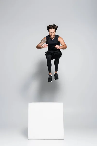 Αθλητικός Αθλητής Πηδά Πάνω Από Κύβο Γκρι Φόντο — Φωτογραφία Αρχείου
