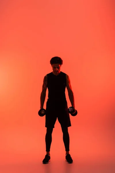 Αθλητικός Άνδρας Αθλητικά Που Κρατάει Αλτήρες Κόκκινο Φόντο — Φωτογραφία Αρχείου