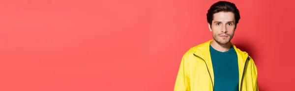 Brunetka Sportowiec Żółtej Kurtce Sportowej Patrząc Kamerę Czerwonym Tle Baner — Zdjęcie stockowe