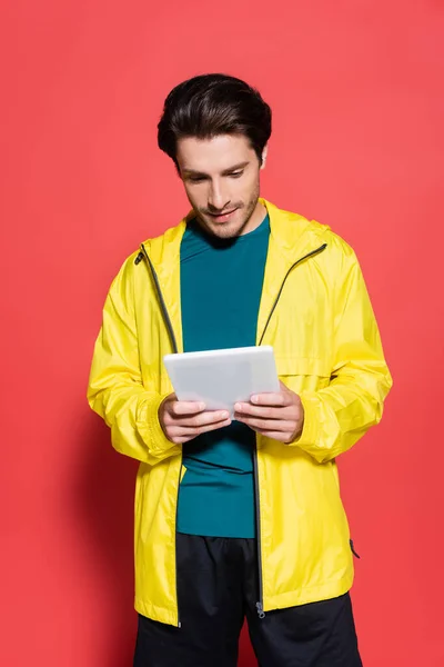 Sportsman Yellow Sports Jacket Using Digital Tablet Red Background — Stock Photo, Image