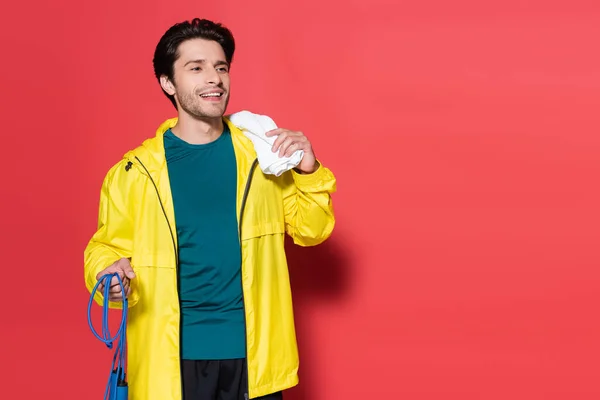 Deportista Sonriente Sosteniendo Cuerda Salto Toalla Sobre Fondo Rojo — Foto de Stock