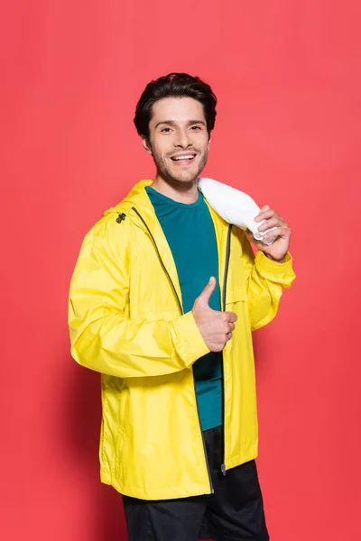 Smiling Sportsman Yellow Sports Jacket Showing Holding Towel Red Background — Stockfoto