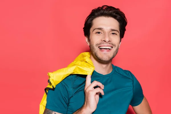 Smiling Sportsman Holding Yellow Sports Jacket Looking Camera Red Background — Stockfoto