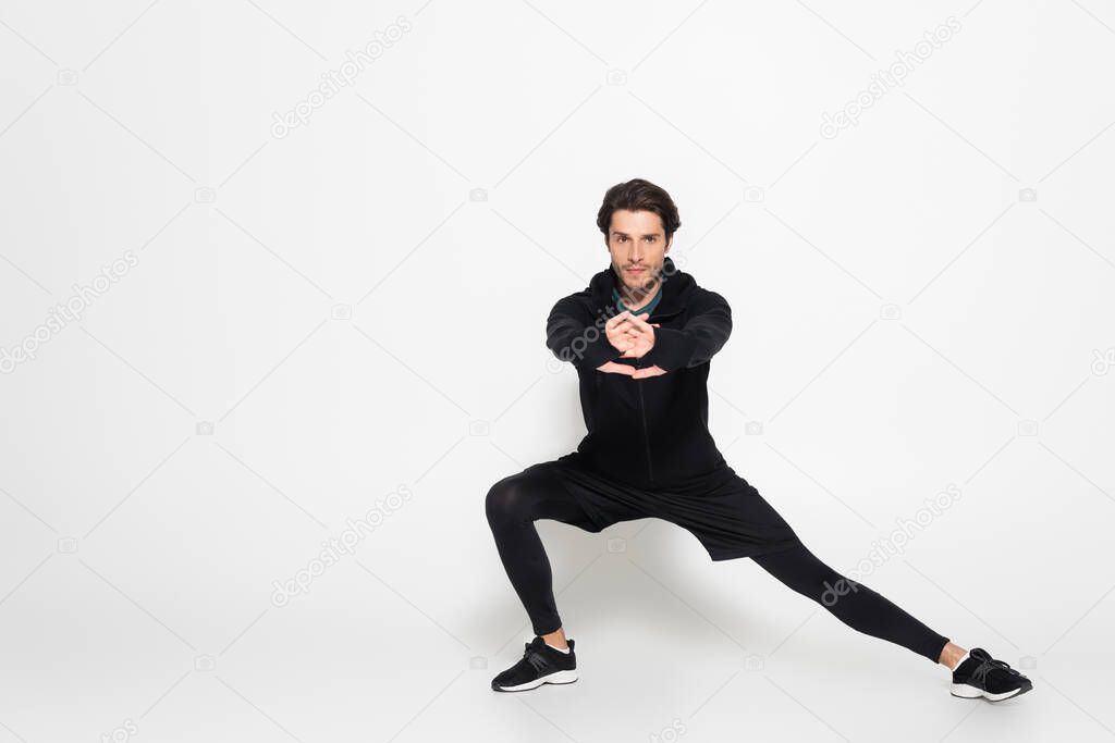 Brunette sportsman looking at camera while training on grey background 