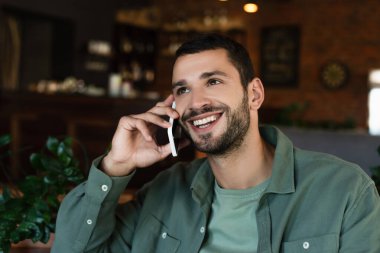 Lokantada akıllı telefondan konuşan mutlu adam gözlerini kaçırıyor.