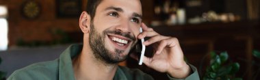 Neşeli adam cep telefonuyla konuşuyor ve kafeye bakıyor, afiş.