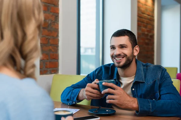 Happy Young Man Holding Coffee Cup Blurred Girlfriend Cafe — Fotografia de Stock