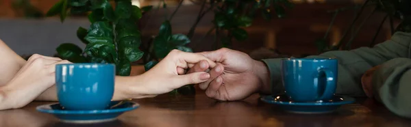 Vista Recortada Pareja Cogida Mano Cerca Tazas Café Pancarta —  Fotos de Stock