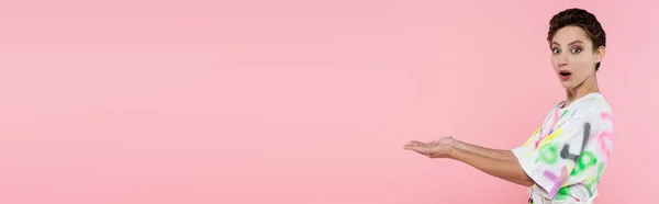 Здивована Молода Жінка Вказує Руками Дивлячись Камеру Ізольовано Рожевому Банер — стокове фото