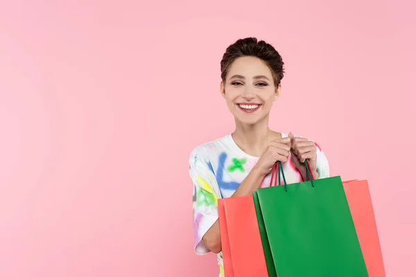 Mujer Morena Complacida Sonriendo Cámara Mientras Sostiene Bolsas Aisladas Rosa — Foto de Stock