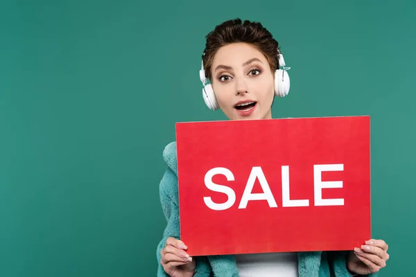 Amazed Woman Headphones Holding Red Card Sale Lettering Isolated Green — Stockfoto