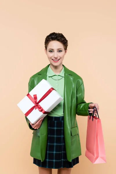 Joyful Woman Gift Box Shopping Bag Smiling Camera Isolated Beige — Stockfoto