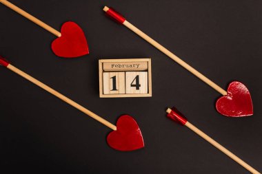Tahta küplerin yakınındaki kalp şeklindeki oklar. 14 Şubat 'ta siyah harflerle izole edilmiş. 