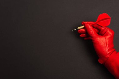 Kırpılmış görüntüde kırmızı eldivenli kadın elinde siyah dart okuyla 