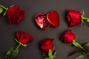 top view of metallic box with red confetti hearts near roses on black clipart