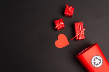 Kalbine yakın geri dönüşüm işareti ve siyah üzerine küçük hediyeler olan çöp kutusunun üst görünümü