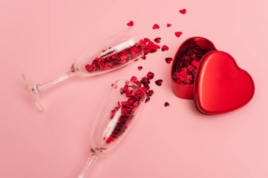 Yüksek açılı şampanya bardakları, konfeti kalpleri, metalik kalp şeklinde pembe kutular.