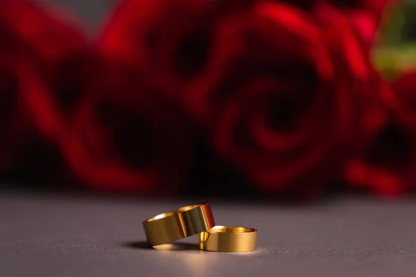 Golden Wedding Rings Blurred Roses Background — Stock Photo, Image