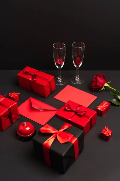 Завернутые Подарки Конверты Возле Металлического Колокола Розы Бокалы Шампанского Черном — стоковое фото