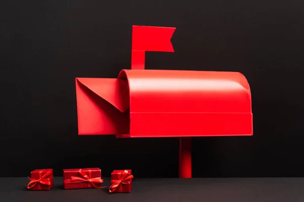 Roter Umschlag Metallischen Briefkasten Neben Kleinen Geschenken Auf Schwarz — Stockfoto