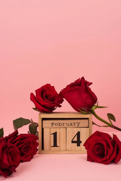 木制立方体附近的红玫瑰 粉红上有14个2月的刻字 — 图库照片