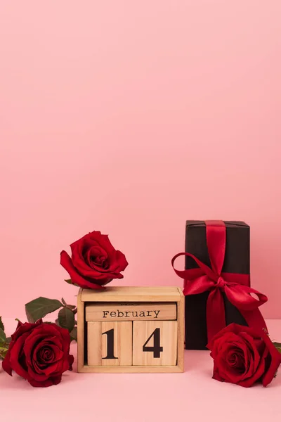 木制立方体附近的红玫瑰 粉红上有14个2月的刻字 — 图库照片