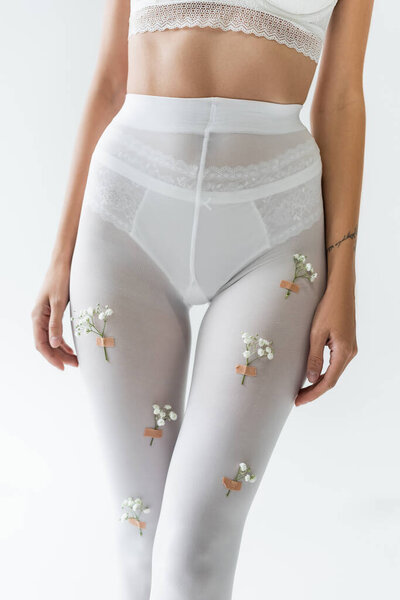 partial view of sexy woman in lace bra, panties and white tights with small flowers isolated on grey