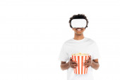 cheerful african american man with big bucket of popcorn gaming in vr headset isolated on white