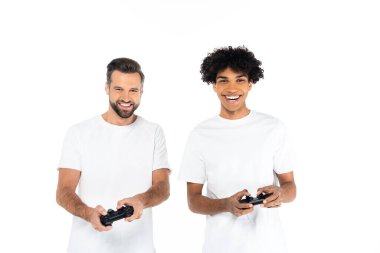KYIV, UKRAINE - 5 ARALIK 2021: Beyazların üzerinde joysticklerle oynayan mutlu ırklar arası erkekler