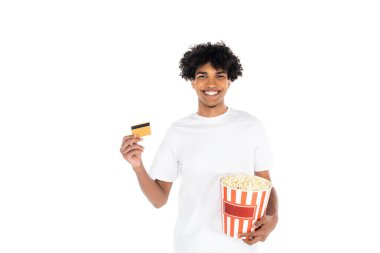 Memnun Afro-Amerikalı adam elinde patlamış mısır ve kredi kartıyla beyazdan izole edilmiş.