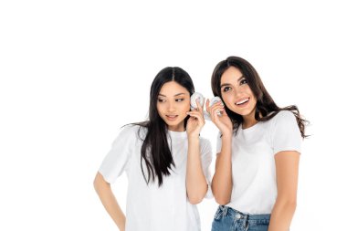 Beyaz ırklar arası gülümseyen, kulaklık tutan ve izole edilmiş müzik dinleyen kadınlar.