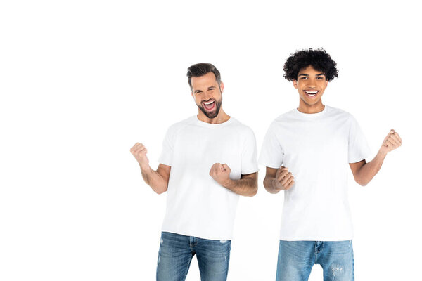 cheerful man shouting and showing triumph gesture with young african american friend isolated on white