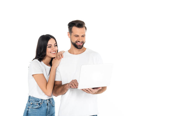 smiling man using laptop near pretty young woman isolated on white