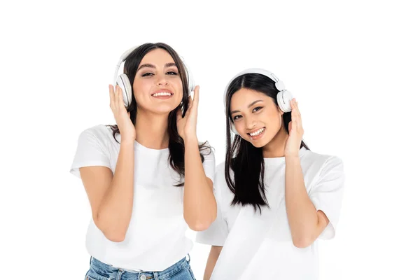 Morena Interracial Mujeres Sonriendo Cámara Mientras Escucha Música Auriculares Aislados — Foto de Stock