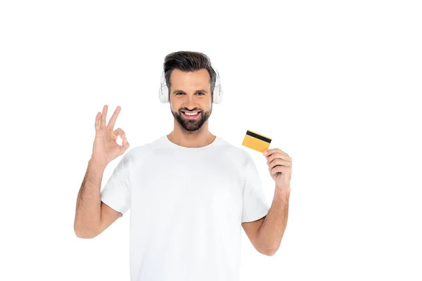 Pleased Man Headphones Holding Credit Card Showing Okay Gesture Isolated — Foto de Stock