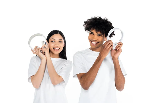 Smiling Interracial Couple Holding Headphones While Listening Music Isolated White — ストック写真